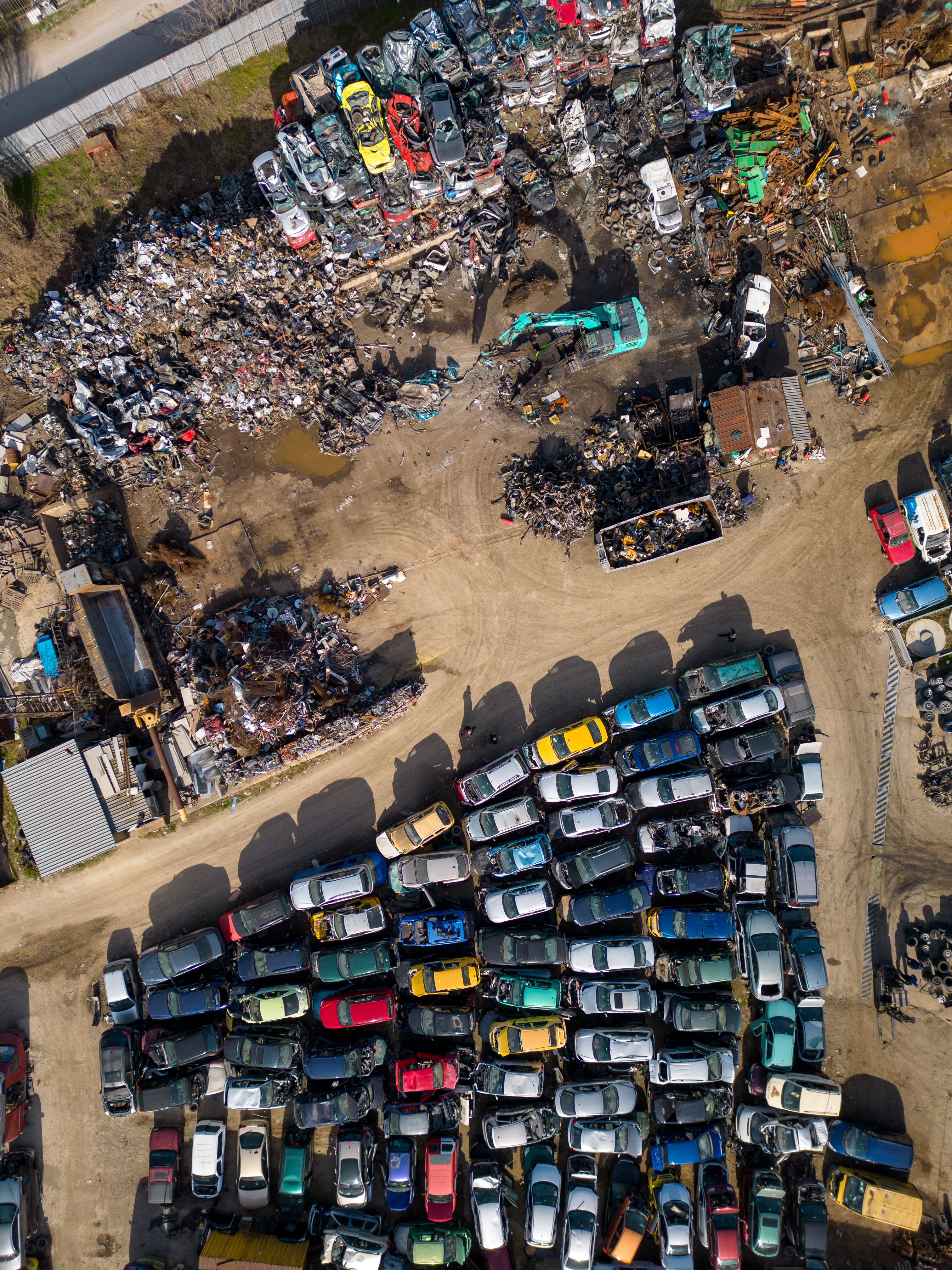 aerial view of a car dump, where a machine is seen separating old cars into scrap.